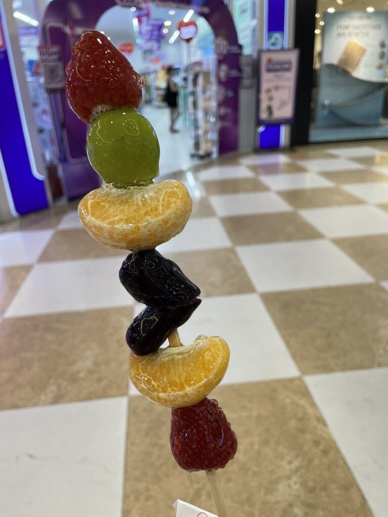 Tanghulu fruit stick with mall in the background 